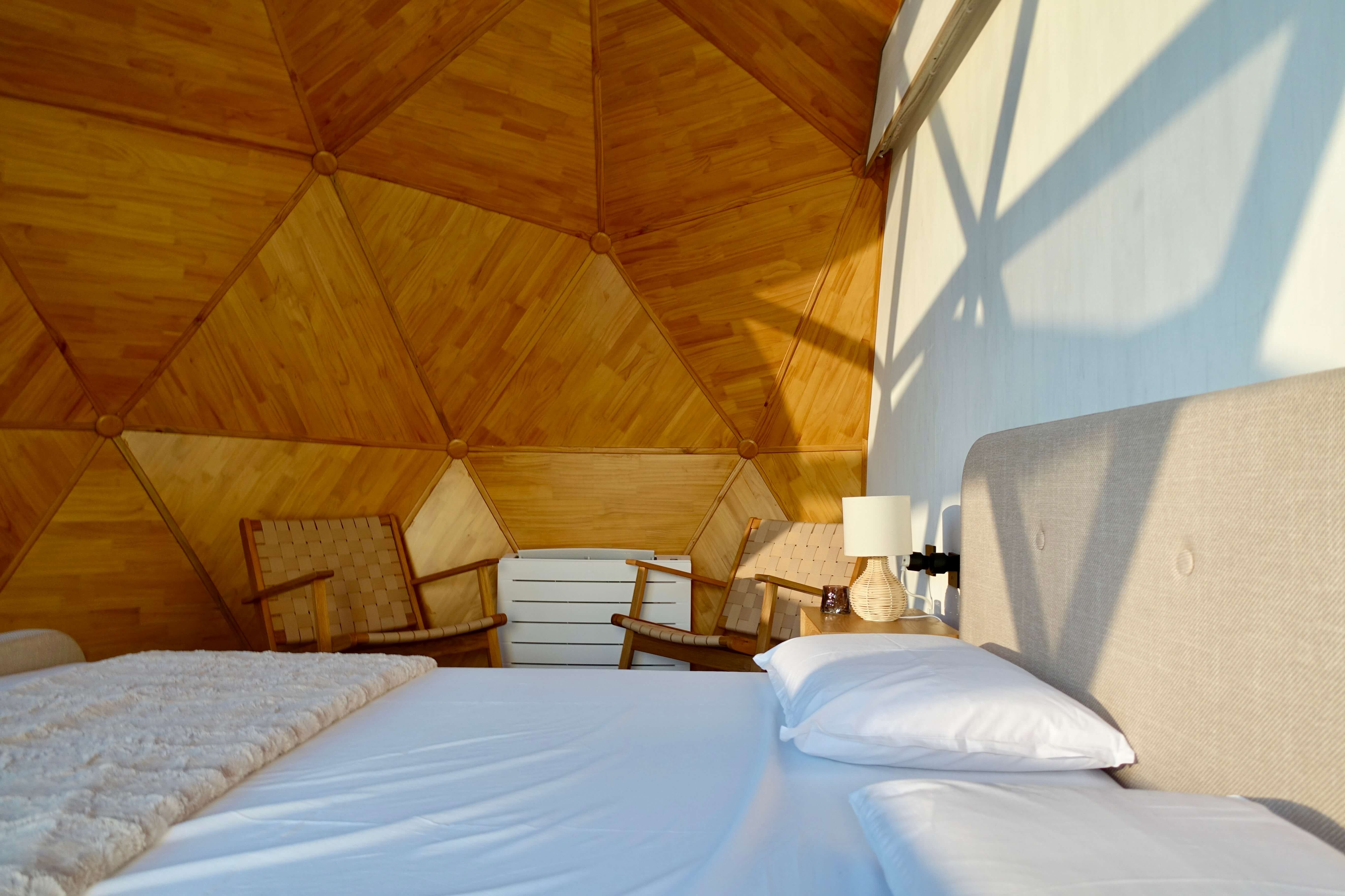 Double bed beneath the timber and glass geodesic dome, positioned for stargazing from inside
