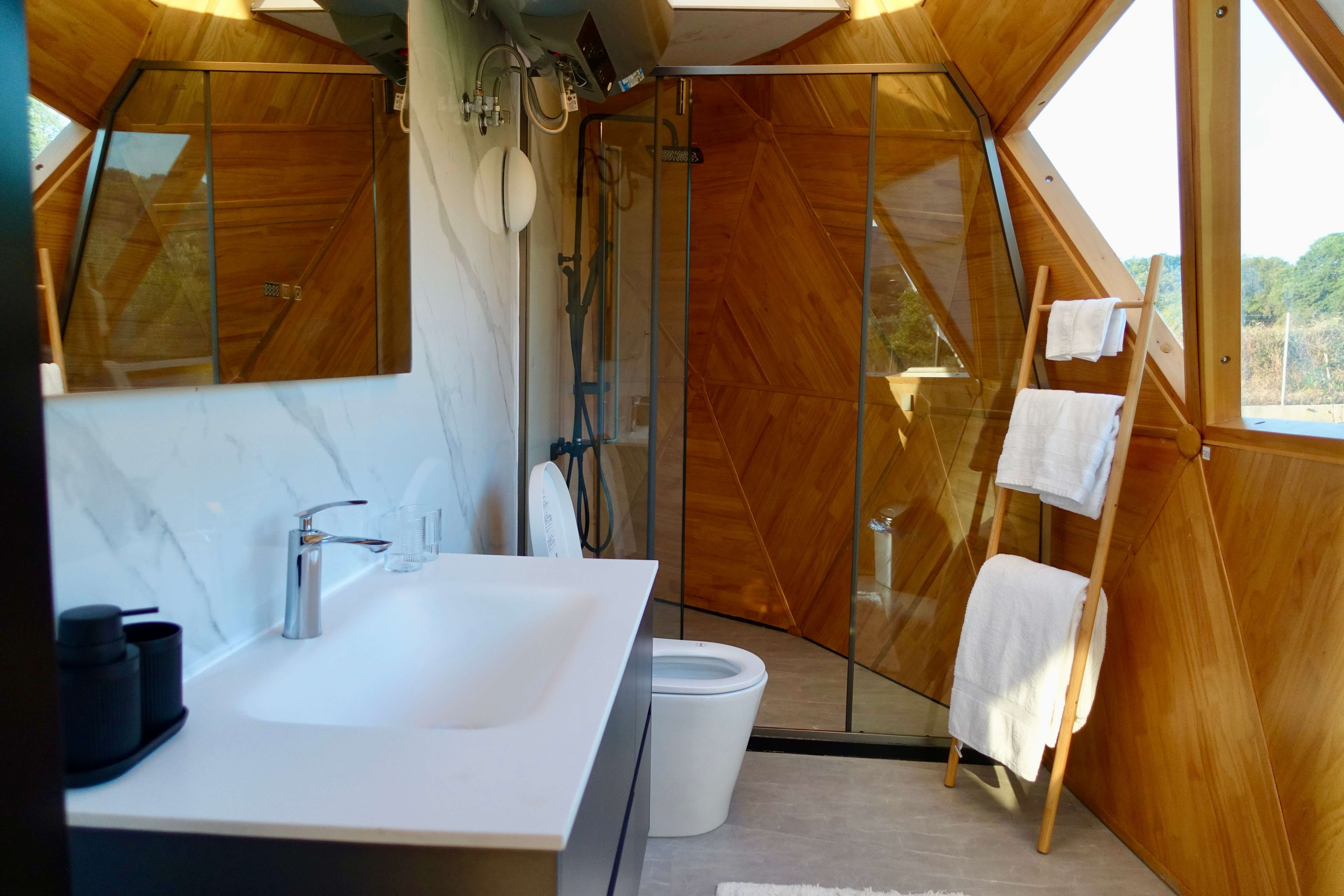 Bathroom inside the dome with marble surfaces, walk-in glass shower and timber panelling